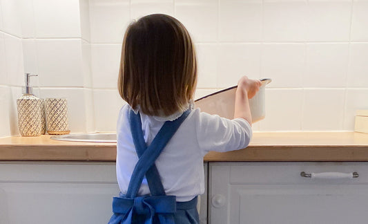 Une petite fille vide une bassine d'eau dans l'évier en totale autonomie