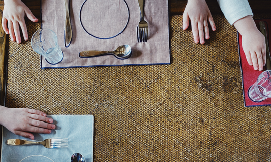 Des enfants posent leurs mains sur des set de table constituant un environnement Montessori