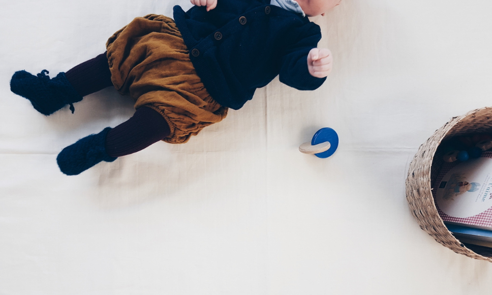 Enfant allongé sur un tapis avec un jouet Montessori